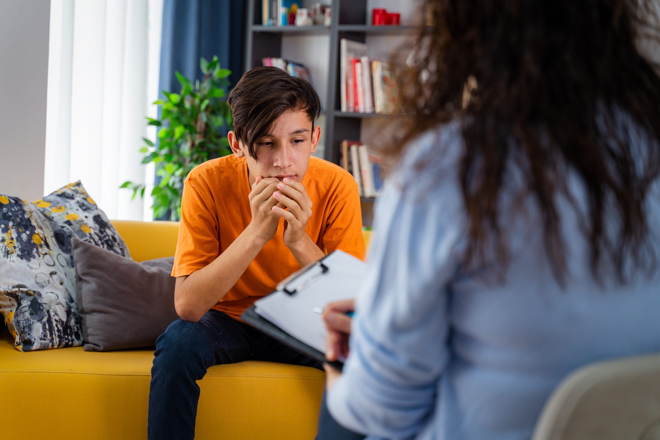 Teen in orange shirt during therapy session.