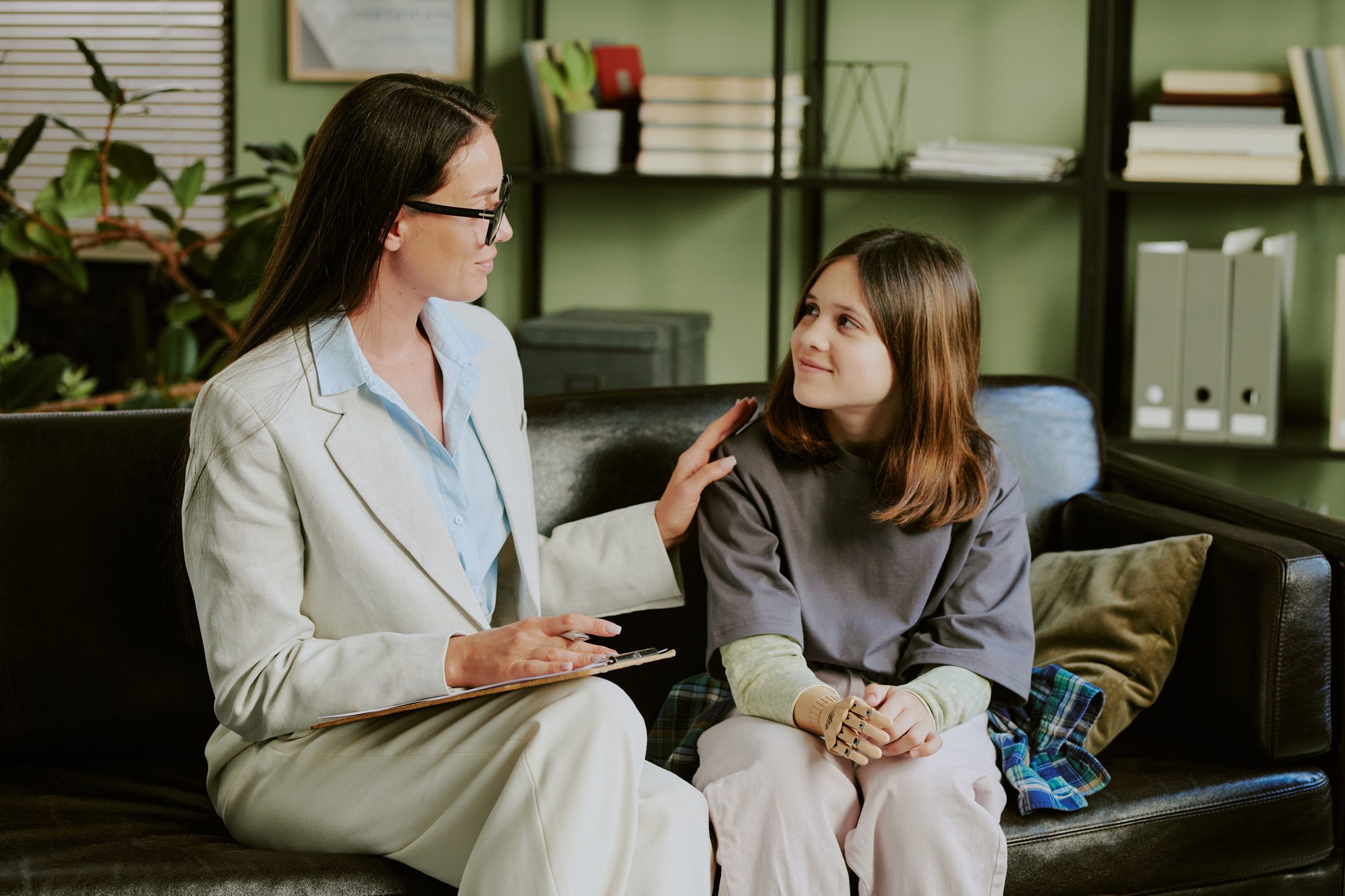 Woman comforting young girl on couch.